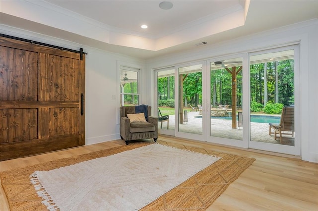 living area featuring healthy amount of natural light, wood finished floors, crown molding, a tray ceiling, and recessed lighting