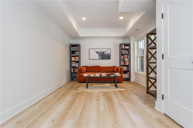 living area featuring a tray ceiling, crown molding, light wood-type flooring, baseboards, and recessed lighting