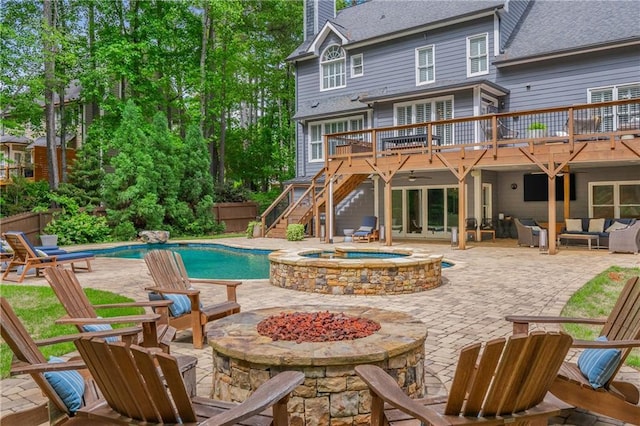 swimming pool with a wooden deck, stairway, an outdoor living space with a fire pit, a patio area, and an in-ground hot tub