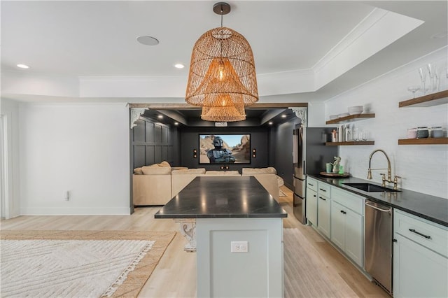 kitchen with a sink, open floor plan, dark countertops, light wood-style floors, and appliances with stainless steel finishes