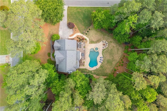 aerial view of a pool area and a tree filled landscape