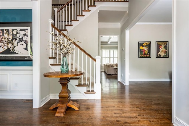 foyer featuring stairway, wood finished floors, ornamental molding, and baseboards