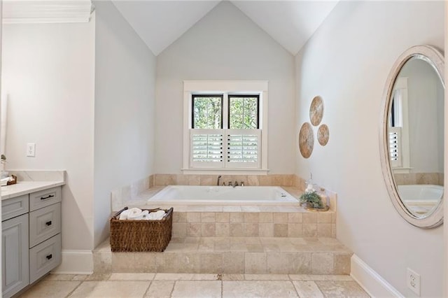 bathroom featuring lofted ceiling, vanity, and tiled tub