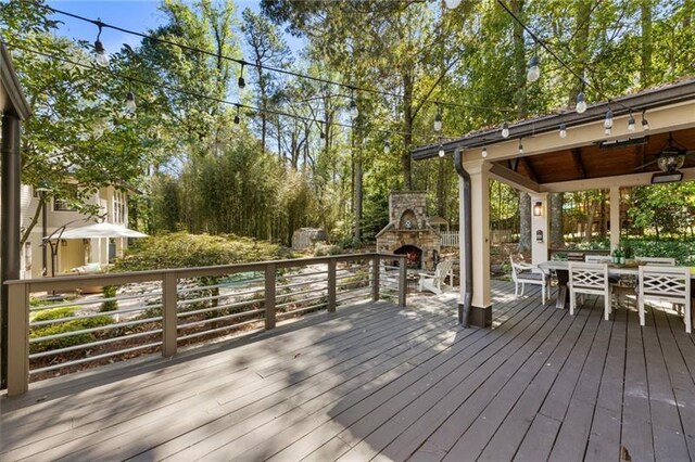 wooden deck with ceiling fan and an outdoor stone fireplace