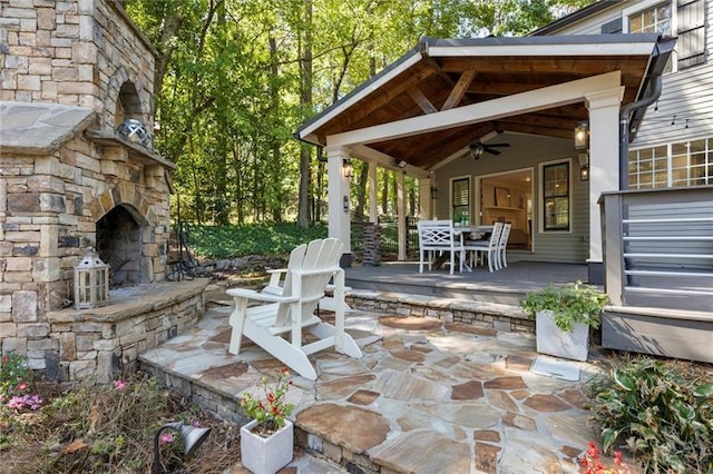 view of patio / terrace featuring ceiling fan and an outdoor stone fireplace