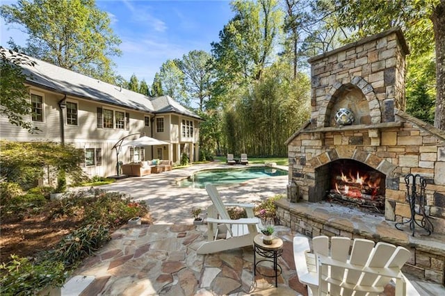 view of pool featuring a patio area and an outdoor living space with a fireplace