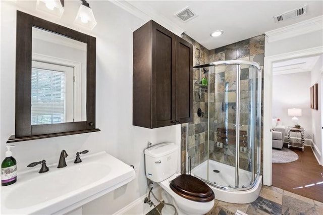 bathroom featuring a shower with shower door, sink, toilet, and crown molding