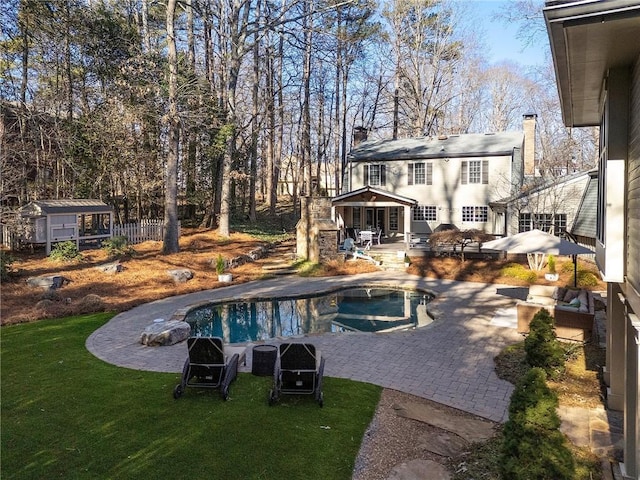 view of swimming pool with a patio area, a yard, and a storage unit