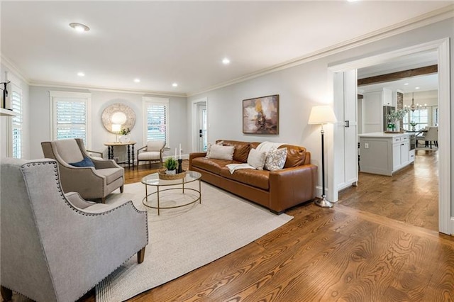 living room featuring an inviting chandelier, crown molding, and light hardwood / wood-style flooring