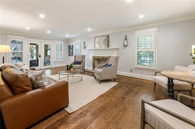 living room with hardwood / wood-style floors, crown molding, french doors, and a stone fireplace