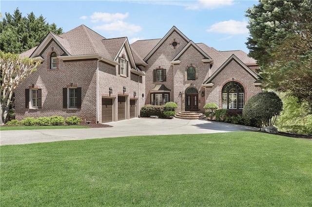 french country inspired facade featuring a garage, brick siding, a front yard, and driveway