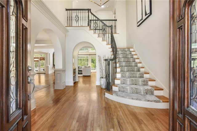 entryway with arched walkways, wood finished floors, a wealth of natural light, and stairway