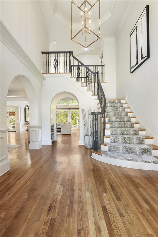 foyer featuring arched walkways, hardwood / wood-style floors, a healthy amount of sunlight, and stairs