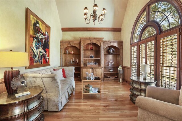 sitting room featuring wood finished floors, high vaulted ceiling, and a chandelier