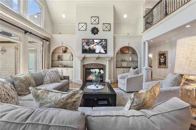 living area featuring a high ceiling, built in shelves, and ornate columns