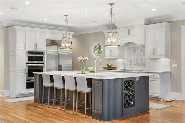 kitchen featuring stainless steel appliances, light countertops, light wood-style floors, and ornamental molding