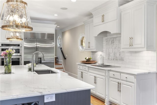 kitchen with white cabinets, stainless steel appliances, a sink, light stone countertops, and decorative backsplash