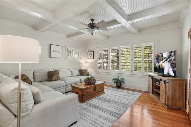living area with beam ceiling, a wealth of natural light, light wood-style floors, and ceiling fan