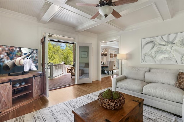 living room with wood finished floors, beam ceiling, ceiling fan with notable chandelier, and coffered ceiling
