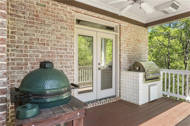 wooden terrace with area for grilling, a ceiling fan, french doors, and a grill