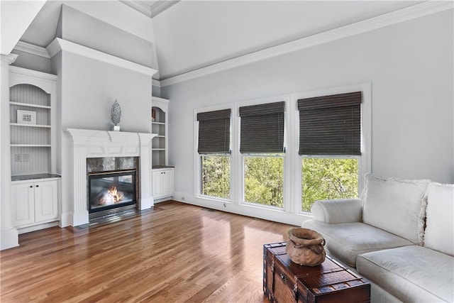 living room with a high end fireplace, crown molding, built in features, and wood finished floors