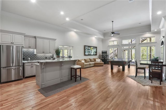 kitchen with gray cabinets, ceiling fan, a kitchen breakfast bar, and freestanding refrigerator