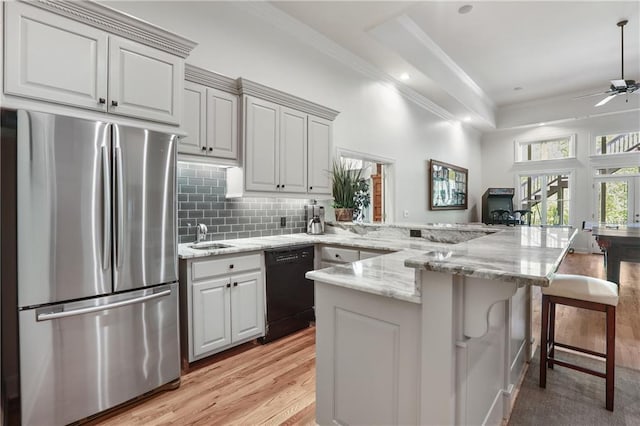 kitchen featuring a peninsula, dishwasher, freestanding refrigerator, and ornamental molding