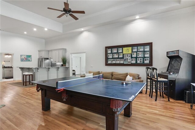 recreation room featuring recessed lighting, a raised ceiling, ornamental molding, light wood-type flooring, and ceiling fan