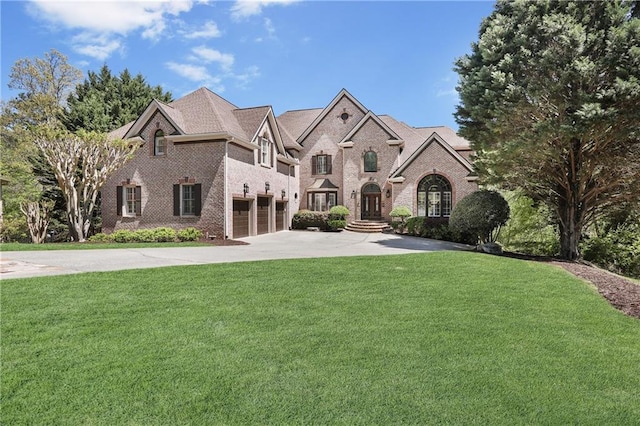 french provincial home with a garage, driveway, a front yard, and brick siding