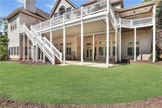 back of property featuring brick siding, a yard, a patio area, and stairs