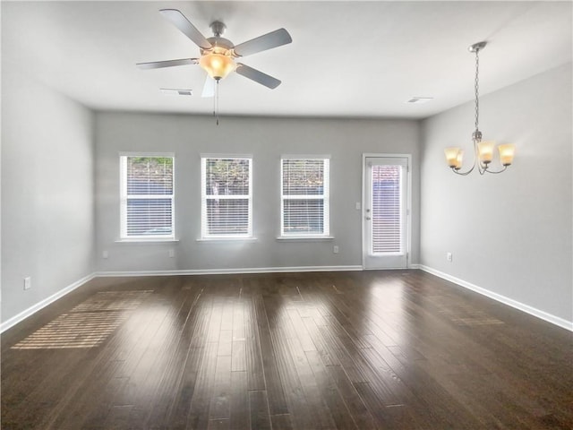 empty room with ceiling fan with notable chandelier and dark hardwood / wood-style floors