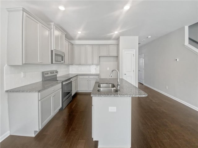 kitchen featuring light stone countertops, sink, stainless steel appliances, and a center island with sink