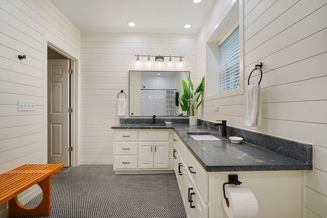 bathroom with tile patterned floors, vanity, a shower with door, and wooden walls