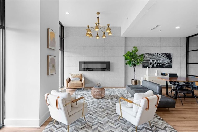 living room with light hardwood / wood-style flooring, a tile fireplace, and an inviting chandelier