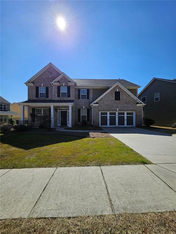 view of front of property with a garage, covered porch, and a front lawn