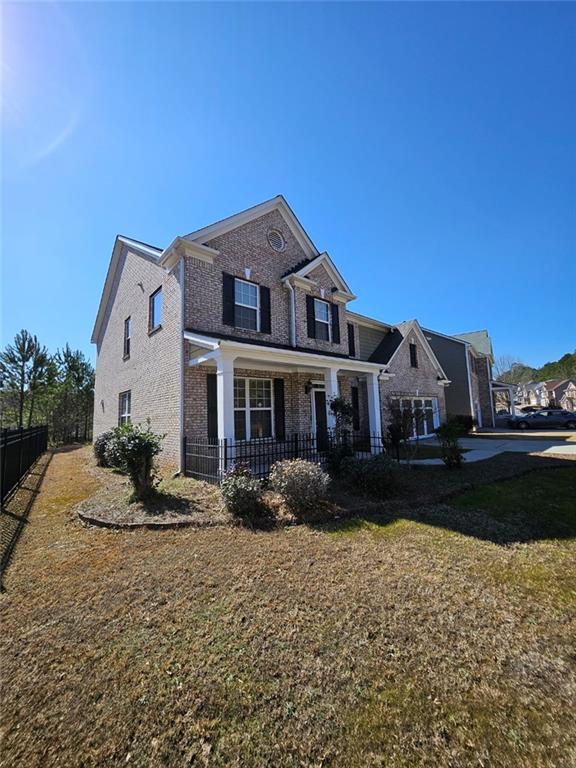 traditional-style home featuring a front yard, brick siding, and fence