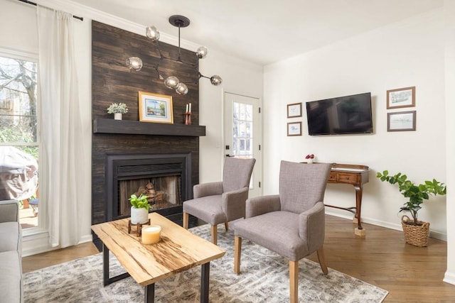 living room featuring a large fireplace, wood finished floors, baseboards, and ornamental molding