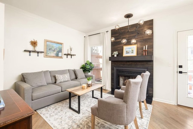 living room featuring a large fireplace, crown molding, baseboards, and wood finished floors