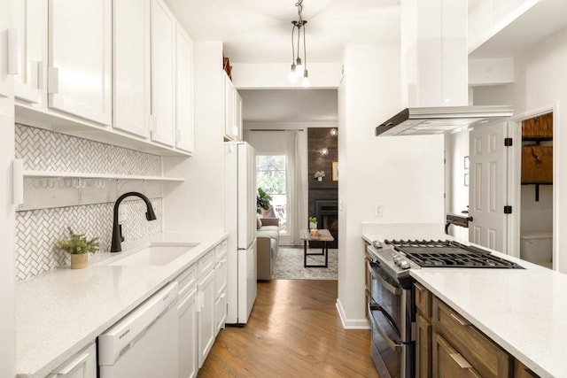 kitchen with light wood-type flooring, a sink, backsplash, white appliances, and wall chimney exhaust hood