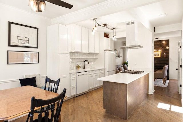 kitchen featuring white appliances, decorative backsplash, light countertops, white cabinets, and wall chimney exhaust hood