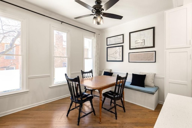 dining area with a ceiling fan, crown molding, wood finished floors, and baseboards