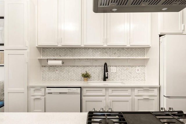 kitchen with under cabinet range hood, decorative backsplash, white appliances, and a sink