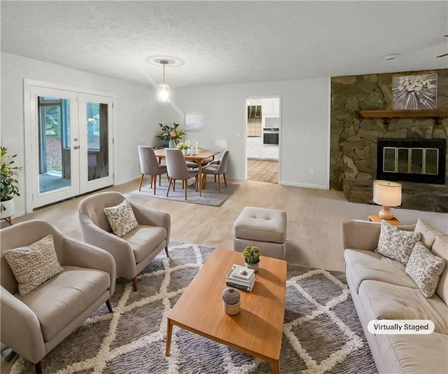 living room with a stone fireplace, french doors, light hardwood / wood-style floors, and a textured ceiling