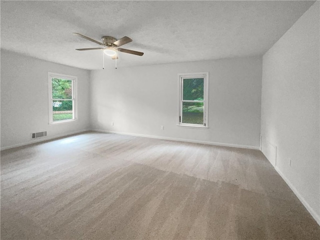 carpeted spare room with ceiling fan and a textured ceiling