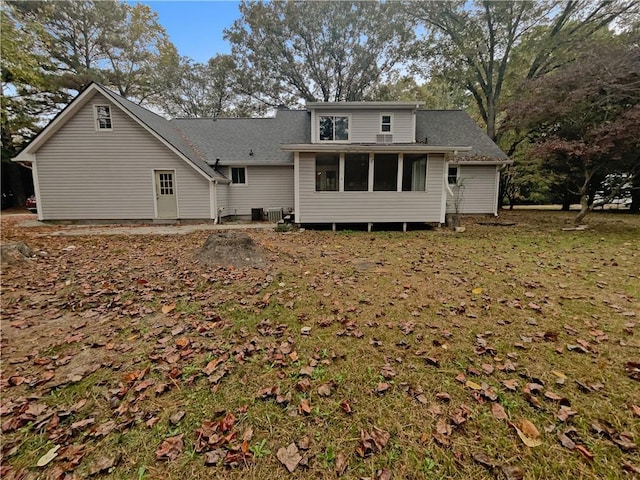 back of property with a lawn and a sunroom