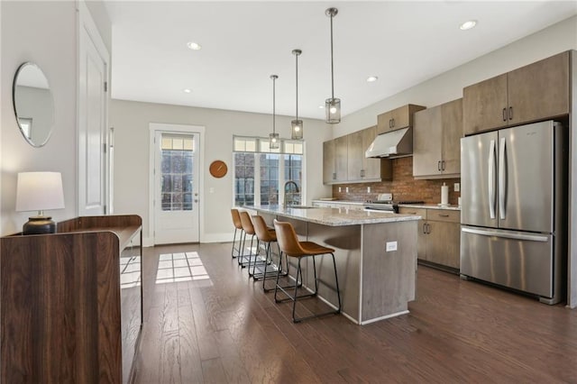 264 Castleberry Station Dr SW, Atlanta, GA 30313 - kitchen with under cabinet range hood, a sink, appliances with stainless steel finishes, tasteful backsplash, and dark wood finished floors