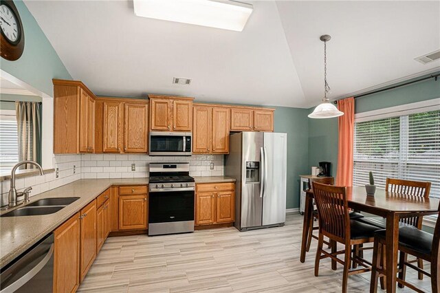 kitchen featuring backsplash, visible vents, appliances with stainless steel finishes, a sink, and lofted ceiling