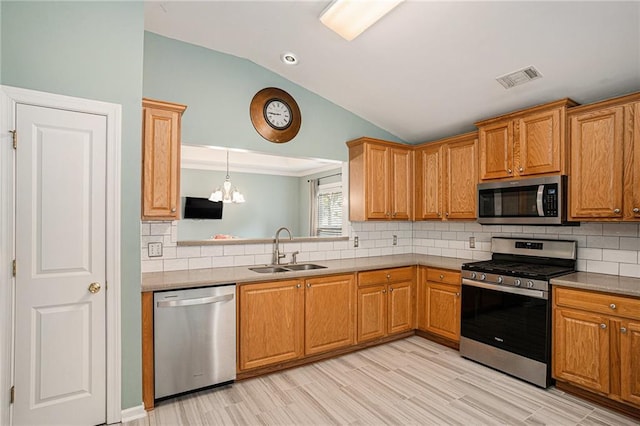 kitchen featuring appliances with stainless steel finishes, a sink, lofted ceiling, backsplash, and visible vents