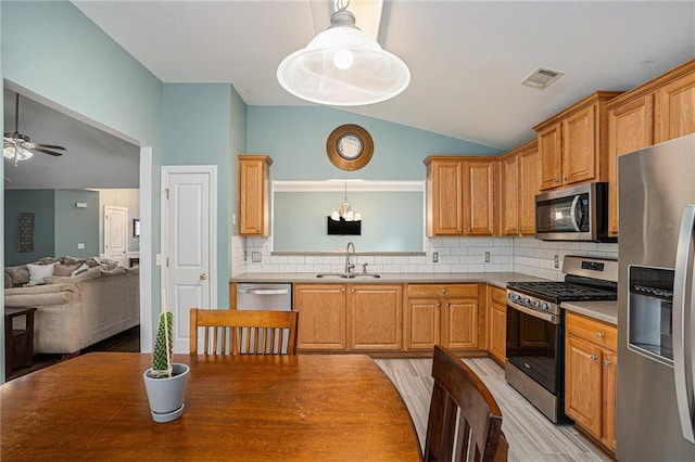 kitchen with a sink, light wood-style floors, stainless steel appliances, vaulted ceiling, and visible vents