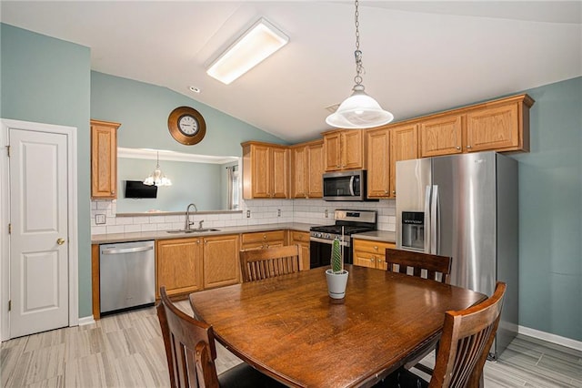 kitchen featuring a sink, stainless steel appliances, decorative light fixtures, decorative backsplash, and vaulted ceiling
